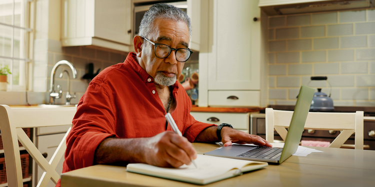 A man takes notes while using his computer